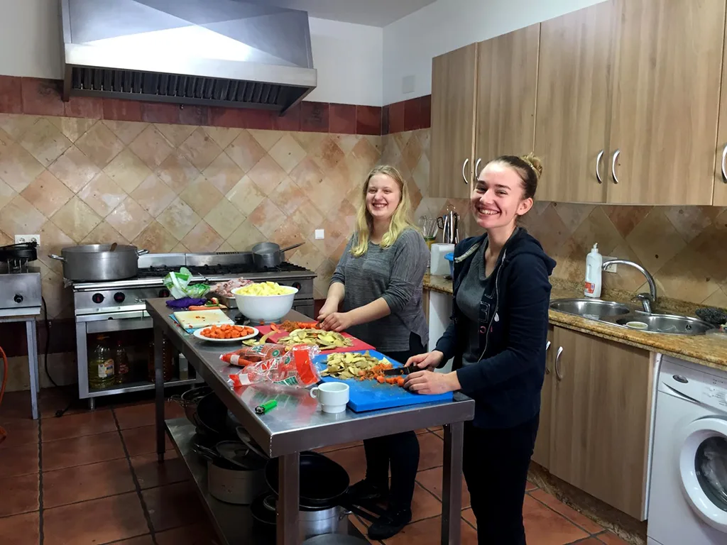 Zwei Jugendliche bereiten in einer Küche Essen auf einer Arbeitsfläche zu.